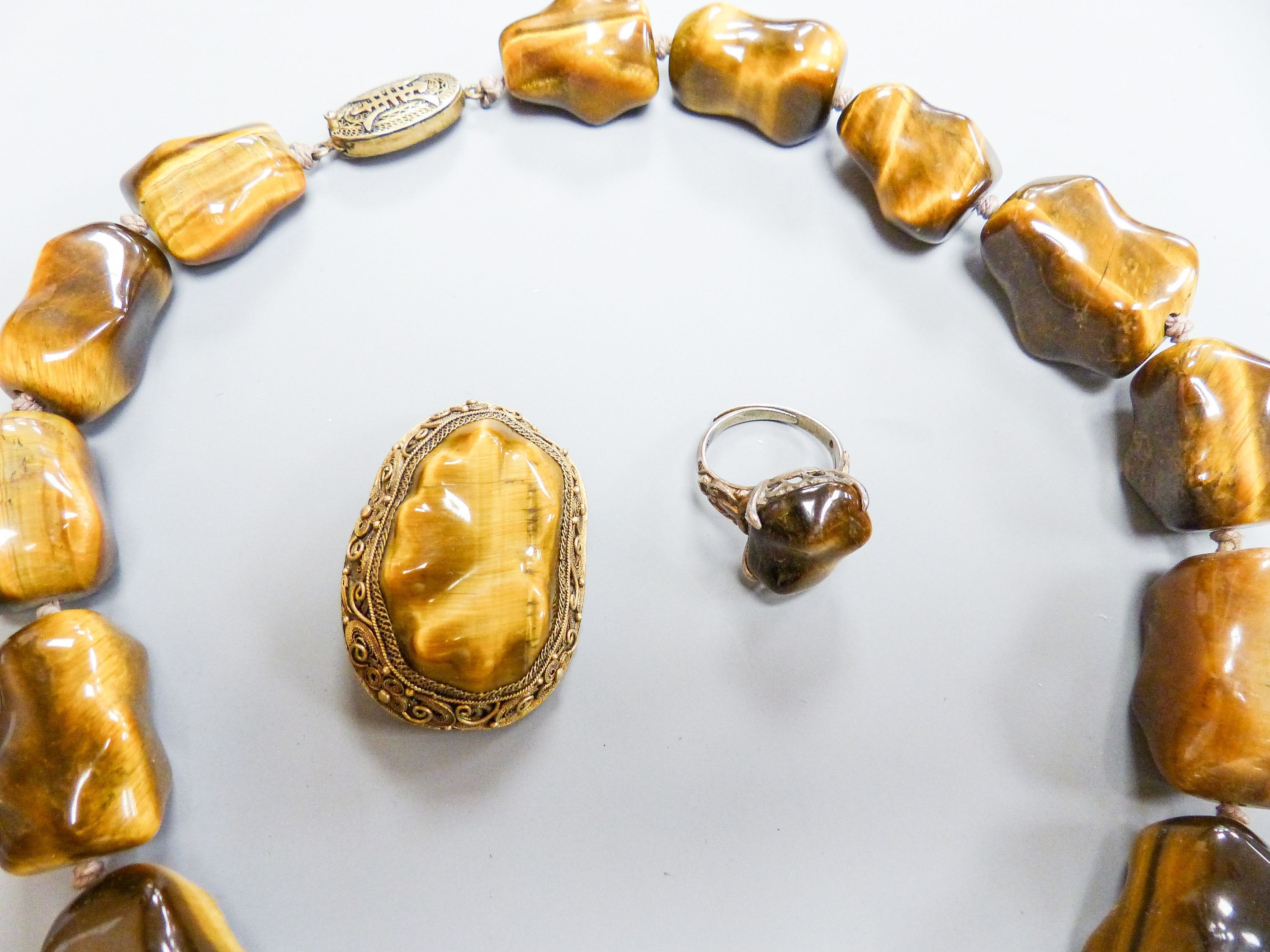 A Middle Eastern gilt white metal and tiger's eye pebble necklace, 48cm and a similar brooch and dress ring.